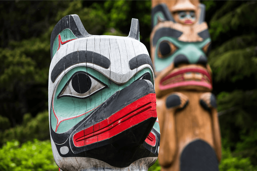 A carved totem pole standing among trees near Ketchikan